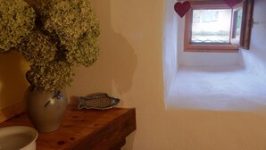 A room with a wooden table, a vase with green foliage, a fish-shaped decorative item, and a window with a view of the outside. - Apartment in Riquewihr Near Vineyards (Riquewihr)