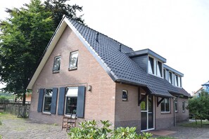 Een herenhuis met twee verdiepingen, een schuin dak en een bakstenen gevel, met een klein voortuintje.