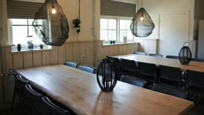 Un salón de conferencias con una larga mesa de madera, sillas negras y lámparas colgantes.