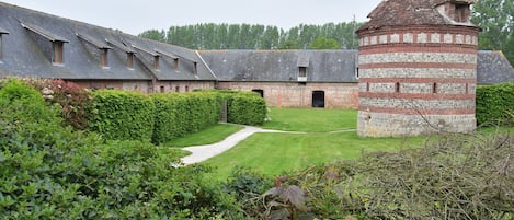 A courtyard with a brick building, a tower, and a pathway.