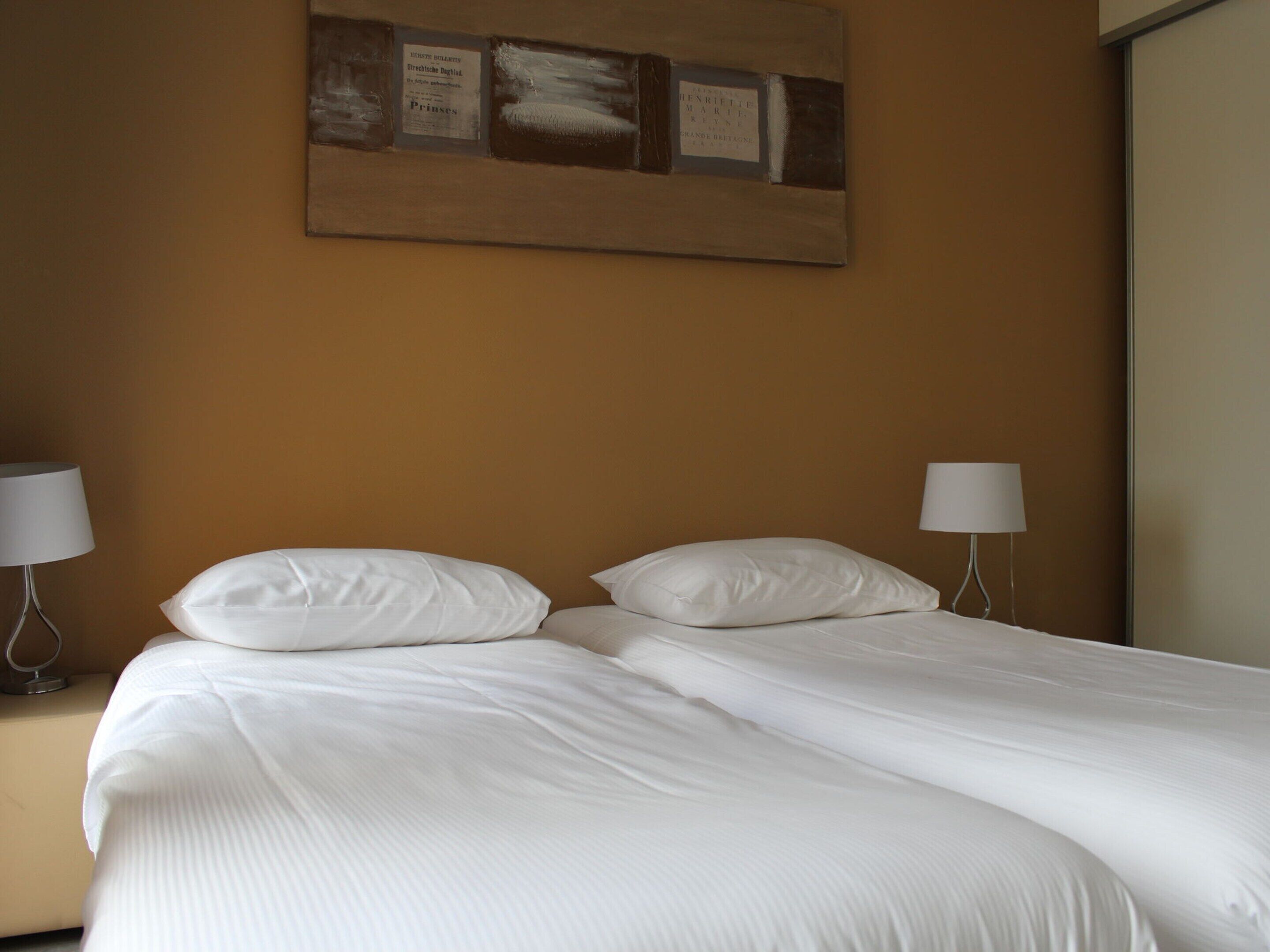 Ein Doppelbett mit weißer Bettwäsche in einem Hotelzimmer.