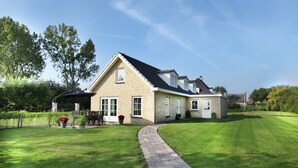 Ein zweistöckiges Haus mit befestigter Auffahrt, Rasen und einem Garten mit Topfpflanzen.