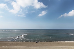 A coastal road with a cyclist, ocean view, and clear sky.