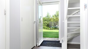 Ein Flur mit einer Schiebetür, die in einen Garten mit Trampolin führt.