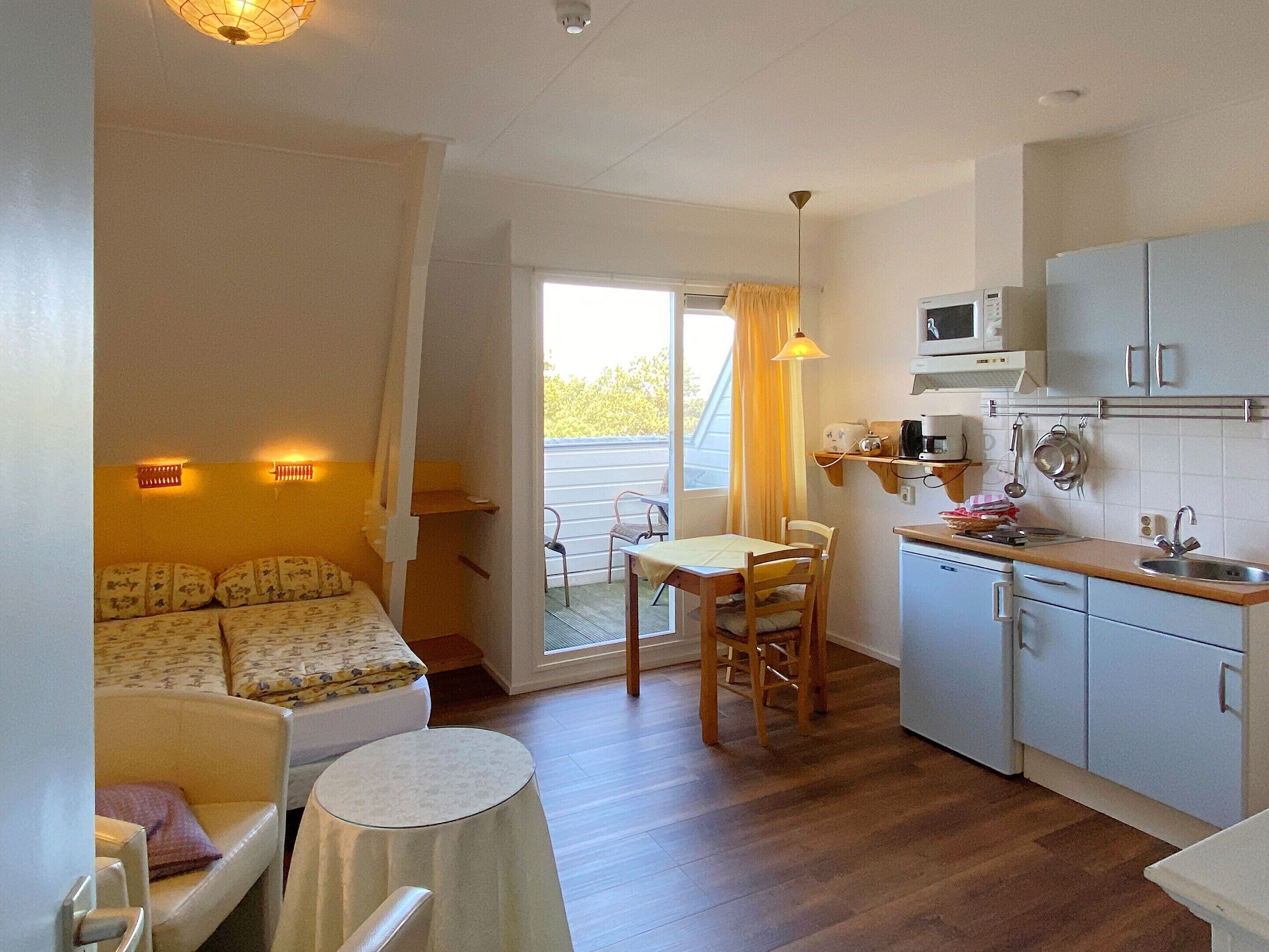 A compact room with a kitchenette, a dining area, and a bed.