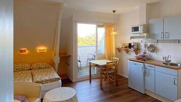 A compact room with a kitchenette, a dining area, and a bed.