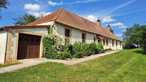A two-story house with a tiled roof, a front garage, and a well-maintained lawn.