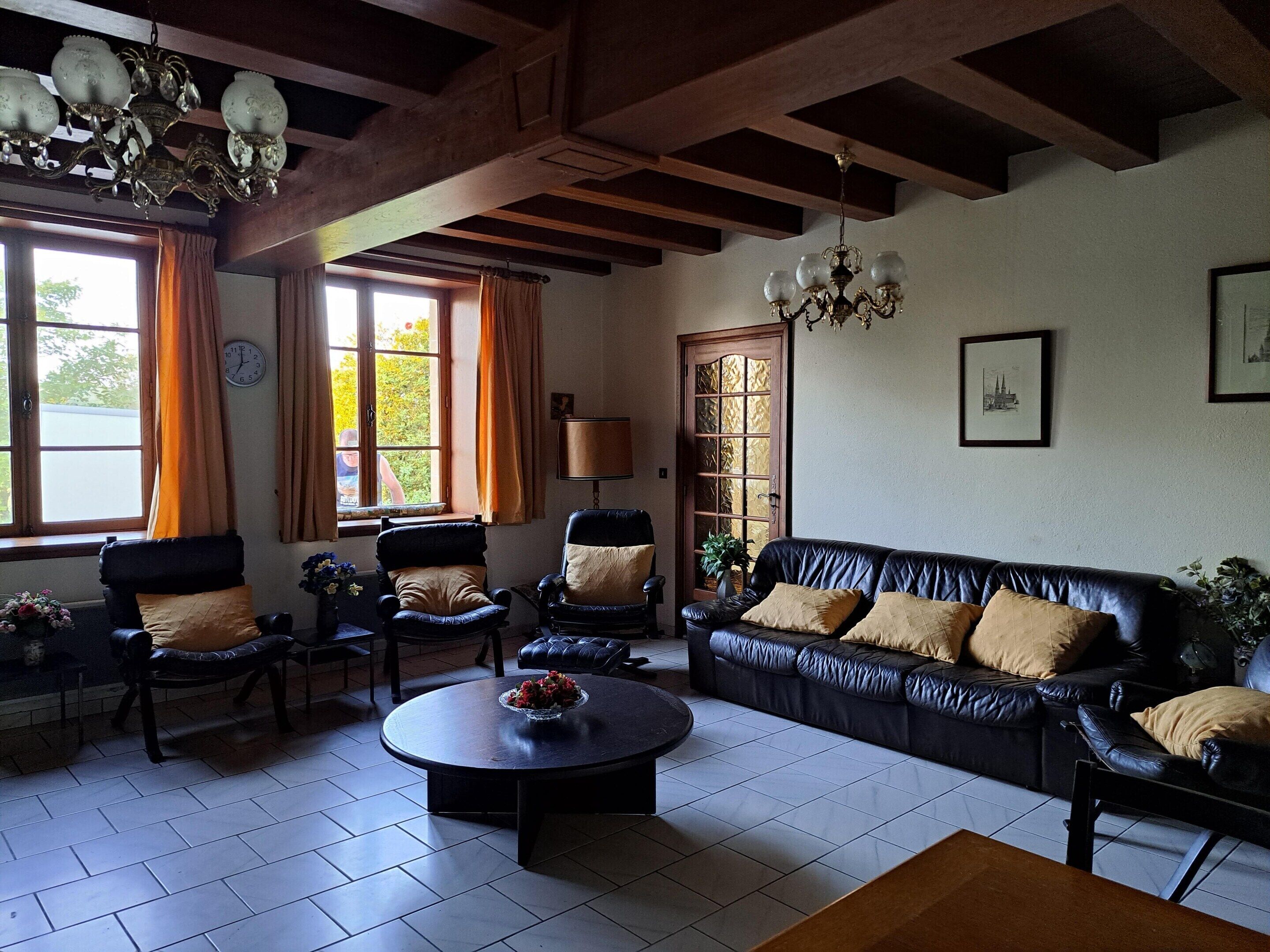 A living room with a sofa, chairs, a coffee table, a chandelier, and a door with glass panels.