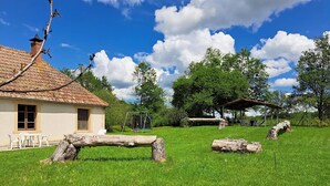 A house with a tiled roof, a swing set, and a wooden bench in a grassy yard.