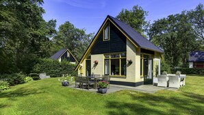 A two-story house with a dark roof and yellow trim, surrounded by lush greenery. - Attractive Holiday Home with Large Garden near Zwolle (Dalfsen)