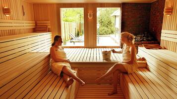 Relax in a serene sauna room with wooden benches and a brick accent wall, offering a peaceful space for conversation and a view of the outdoors.