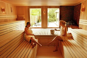Un sauna en bois avec des bancs, une vue sur l’extérieur et un mur en pierre.