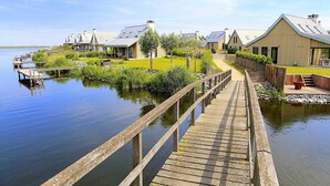 A wooden pier leading to a row of modern houses by a calm lake. - Villa Oesterdam Deluxe 6 Persons (Tholen)