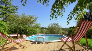 A wooden deck with a swimming pool, surrounded by red and white striped lounge chairs. - Village House in La Caunette With Pool (La Caunette)