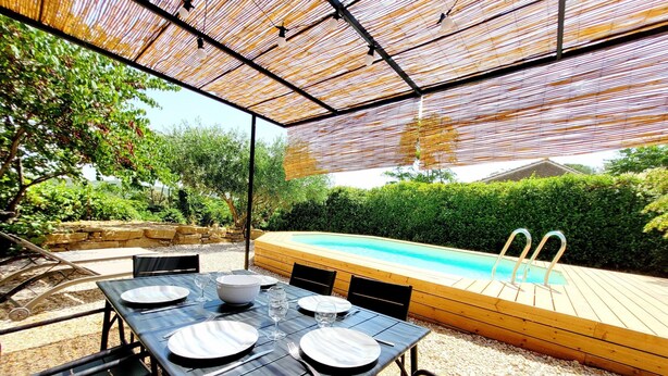 An outdoor dining area with a pool, surrounded by greenery and stone walls. - Village House in La Caunette With Pool (La Caunette)