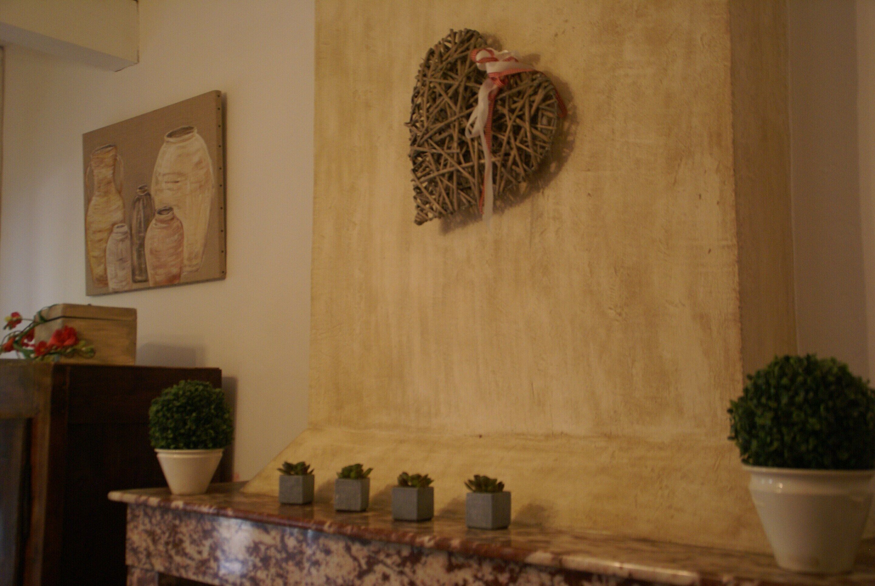 A room with a marble countertop, small potted plants, a painting, and a woven heart decoration on the wall.