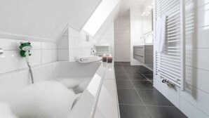 Une salle de bain moderne équipée d’une baignoire, d’un porte-serviettes et d’une pomme de douche.