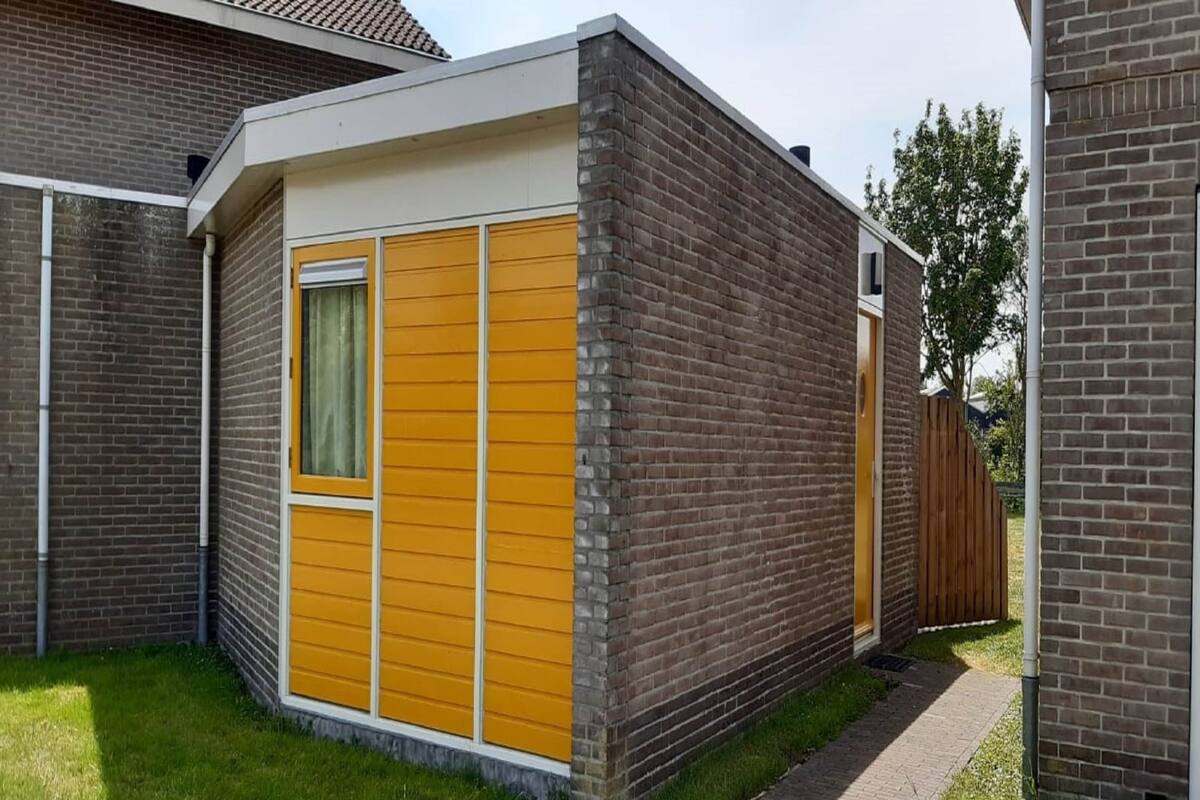 A small, single-story building with a brick exterior and a yellow front wall.