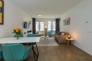 A modern living room with a dining area, a sofa, a TV, and a lamp. - Apartment in Zoutelande Near Sunny Beach (Zoutelande)