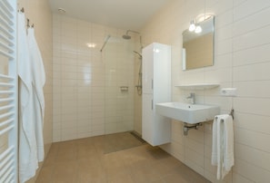 A modern bathroom with a glass-enclosed shower, a white sink, and a mirror above it. - Apartment in Zoutelande Near Sunny Beach (Zoutelande)