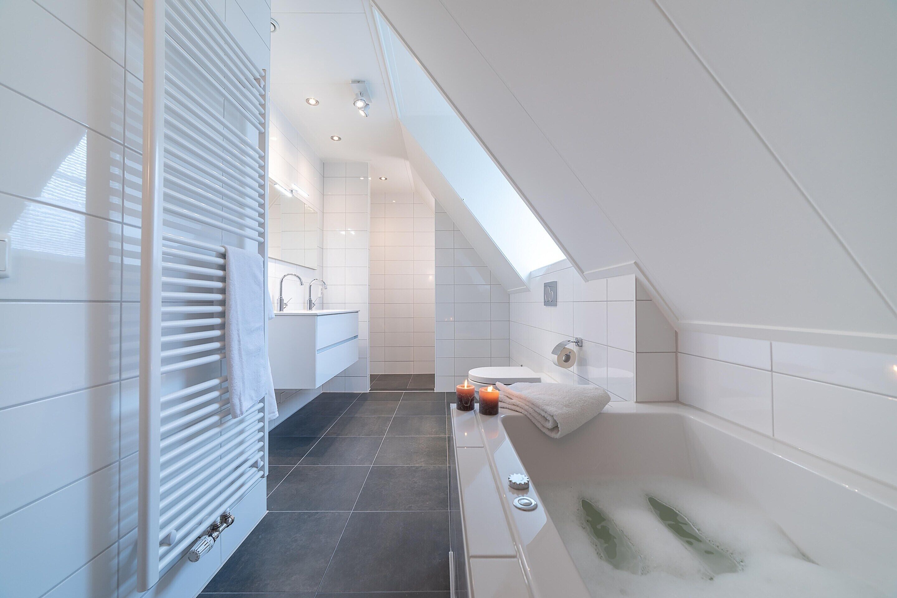 Een moderne badkamer met een bad, een toilet en een wastafel met spiegel.