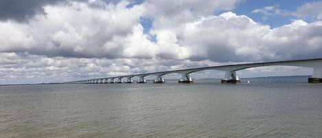 Un long pont à arches multiples enjambant une étendue d’eau, avec une côte rocheuse au premier plan.