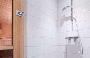 A shower area with white tiles, a wooden panel wall, and a metal showerhead. - Family Villa in the Oosterschelde National Park (Colijnsplaat)