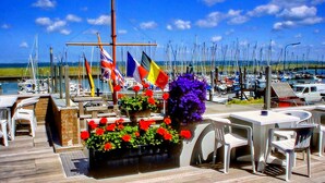 A marina with boats docked, outdoor seating, and flags.