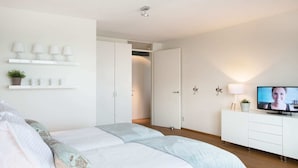 Ein modernes Schlafzimmer mit Bett, Fernseher, Kleiderschrank und Regal mit Dekoration.