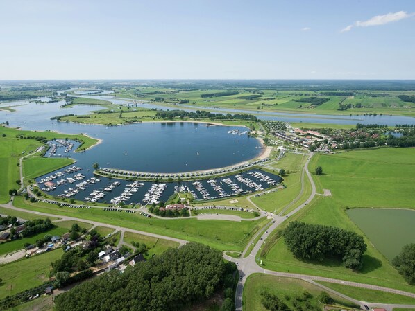 An aerial view of a marina with boats docked, surrounded by green fields and a small town.