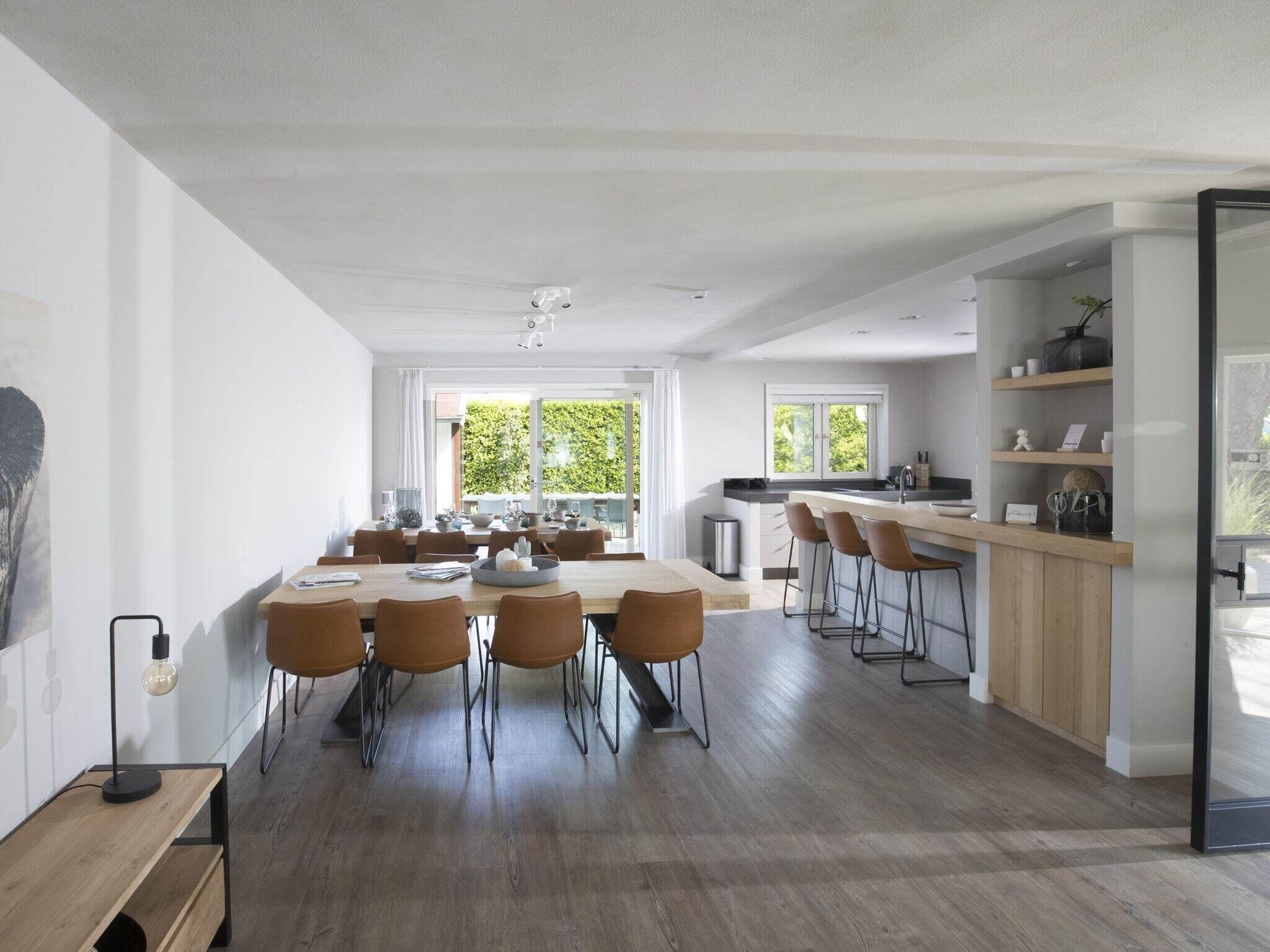 A spacious kitchen with a dining area, wooden flooring, and large windows.
