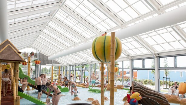Un parc aquàtic interior amb tobogans, zones de jocs d'aigua i una gran atracció aquàtica.