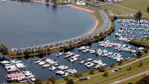 Vista aèria d'una marina amb nombroses embarcacions amarrades, envoltada per una zona residencial amb cases i una extensa massa d'aigua.