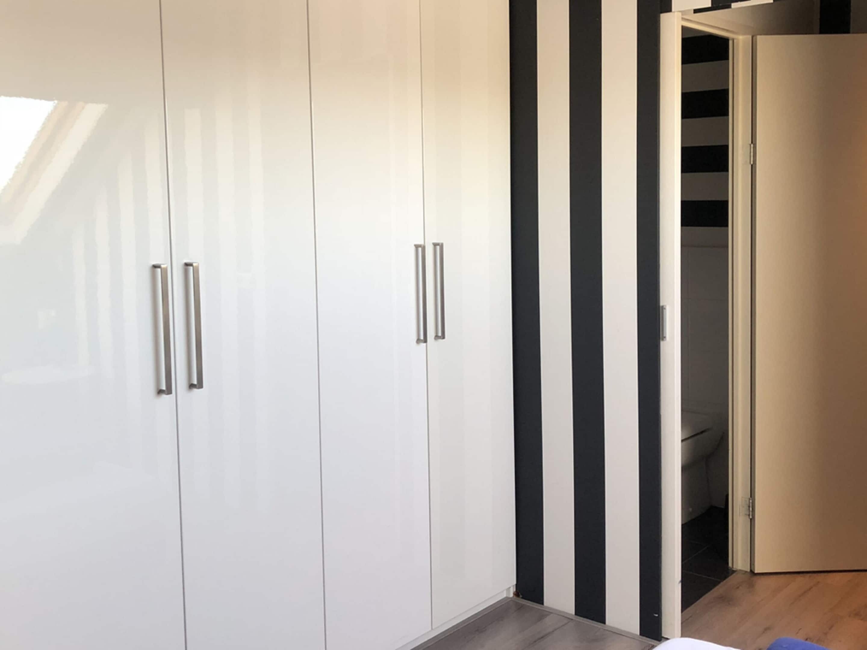 Ein modernes Zimmer mit weißen Schränken und einer schwarz-weiß gestreiften Wand.