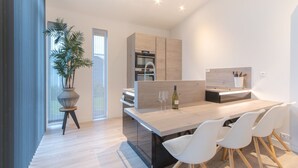 A modern kitchen with a central island, white chairs, and a potted plant. - Cozy Chalet with Fireplace near Oosterschelde (Wemeldinge)