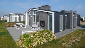 A modern house with a patio, outdoor seating, and a garden. - Cozy Chalet with Fireplace near Oosterschelde (Wemeldinge)