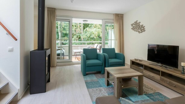 Een moderne woonkamer met een open haard, een televisie en een balkon met tuinmeubilair.