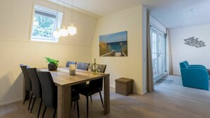Een eethoek met een houten tafel, zwarte stoelen en een potplant.