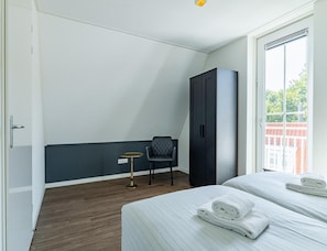 A hotel room with a bed, a chair, a small table, and a wardrobe. - Apartment Near South Beach With Sauna (Koudekerke)