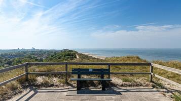 A bench overlooking a beach with a clear view of the ocean and distant city skyline.