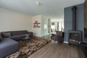 Un salon moderne comprenant un canapé, une table basse, un tapis, une cheminée et un fauteuil.