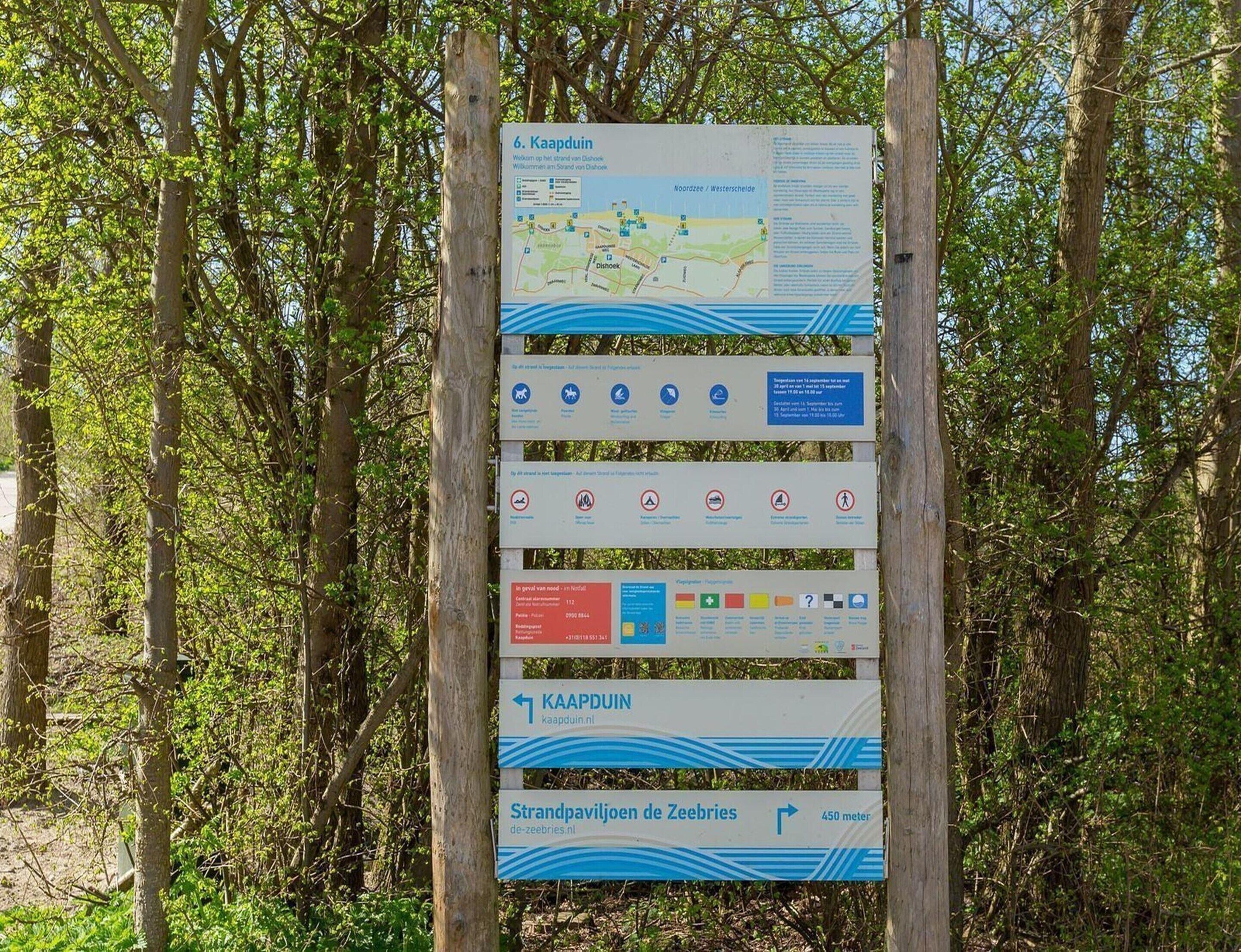 A directional signpost with multiple panels, including a map and various symbols indicating facilities and regulations.