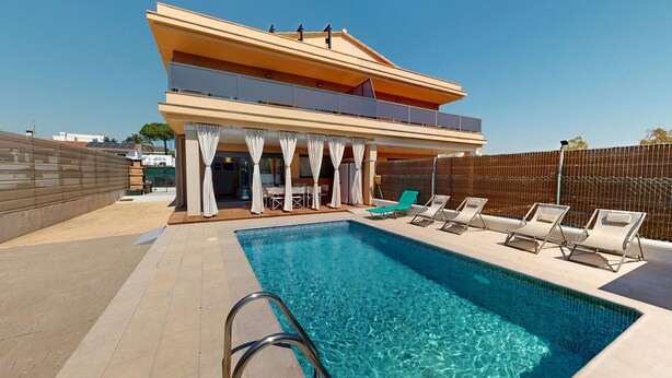 Ein modernes, zweistöckiges Gebäude mit Swimmingpool, Außenbereich mit Sitzgelegenheiten und einer überdachten Terrasse.