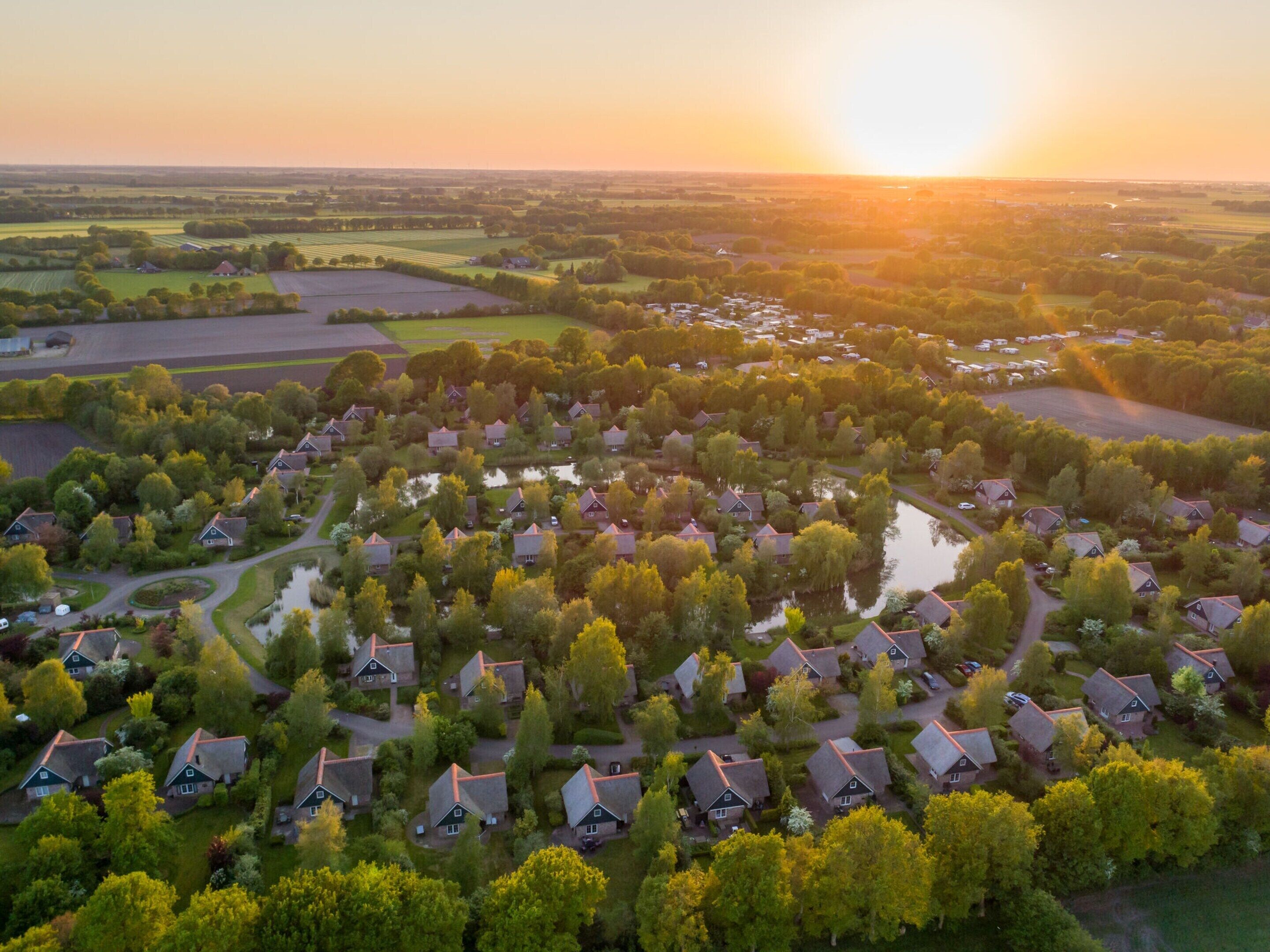 Ett flygbildsbild av ett bostadsområde med hus, vägar och en vattenyta.