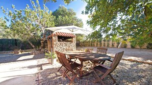 Une terrasse extérieure avec un four en pierre, une table en bois et des chaises.