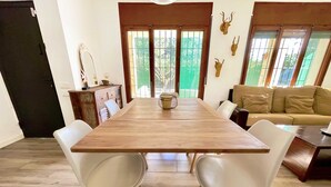 Un coin repas avec une table en bois et des chaises blanches, un canapé et des bois de cerf décoratifs accrochés au mur.