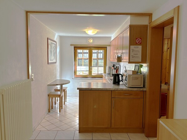 A kitchen with wooden cabinets, a countertop, a kettle, and a microwave. - Chalet Medi (Zermatt)