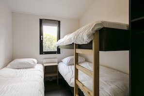 Un dormitorio con dos camas individuales, una ventana y un radiador.