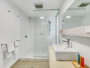 Un baño moderno con ducha, lavamanos y espejo.
