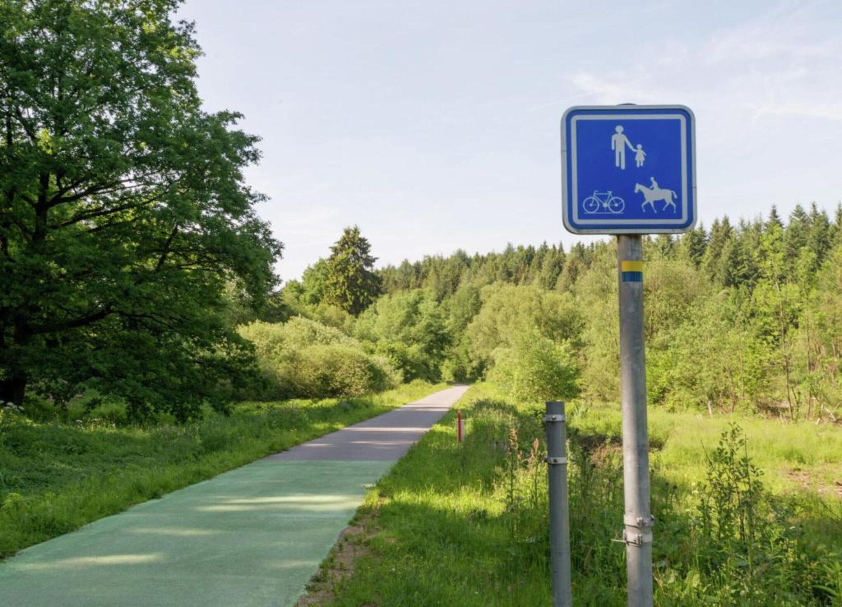 A blue sign indicating a shared path for pedestrians, cyclists, and horseback riders.